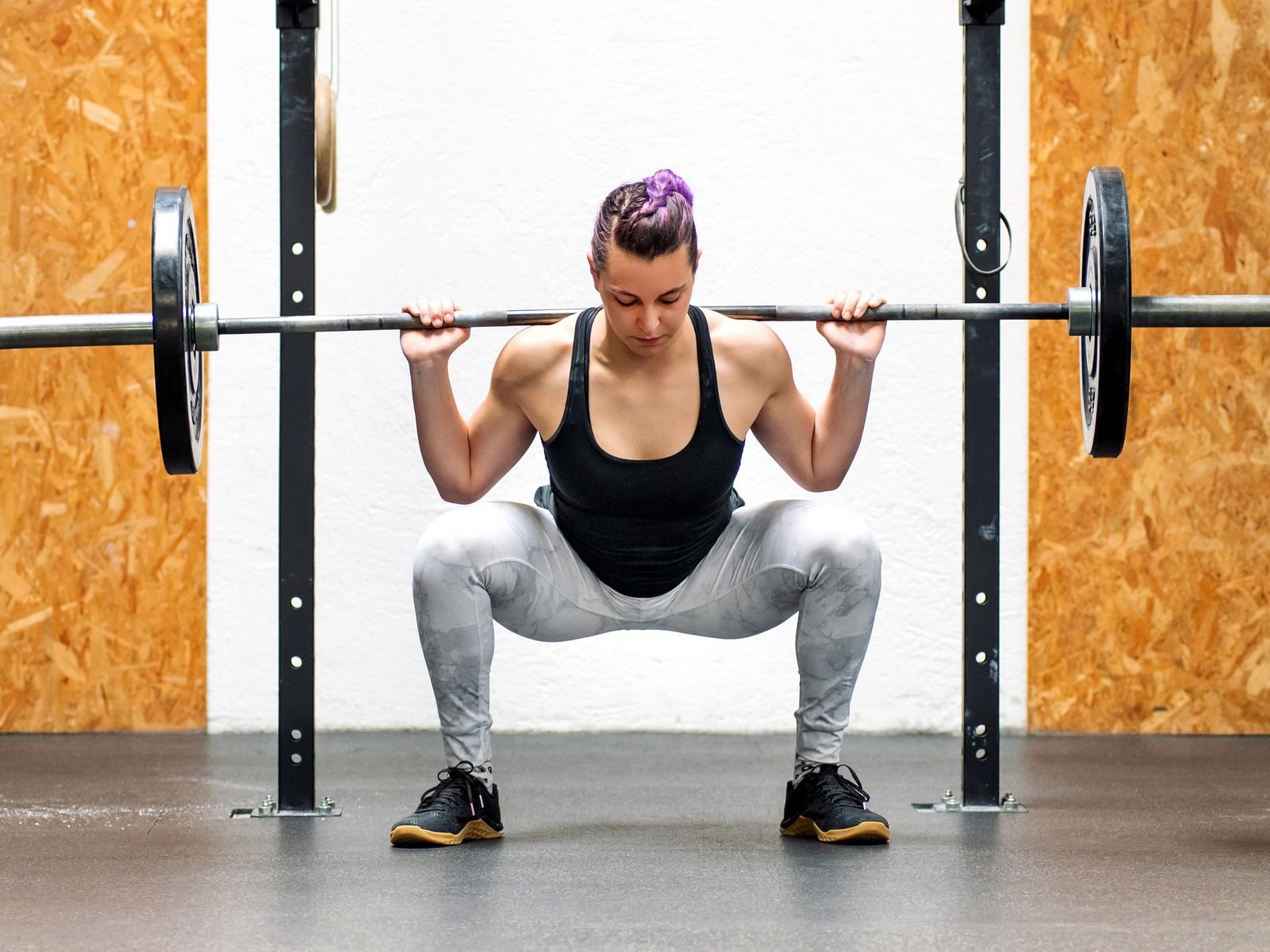 Home young girl doing a back squat with a barbell